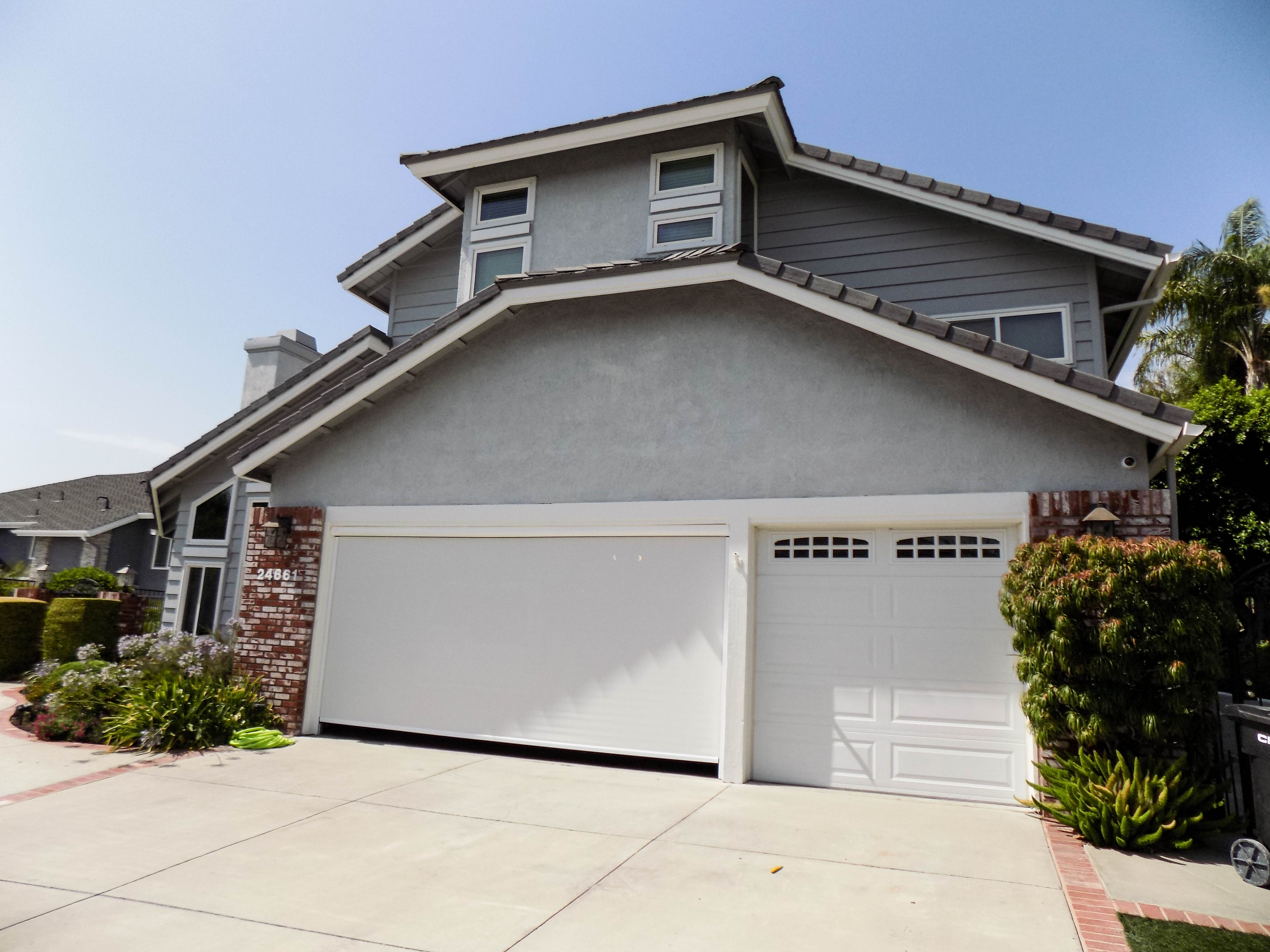 Motorized Power Screen with white solar screen and white housing
	 on a garage door