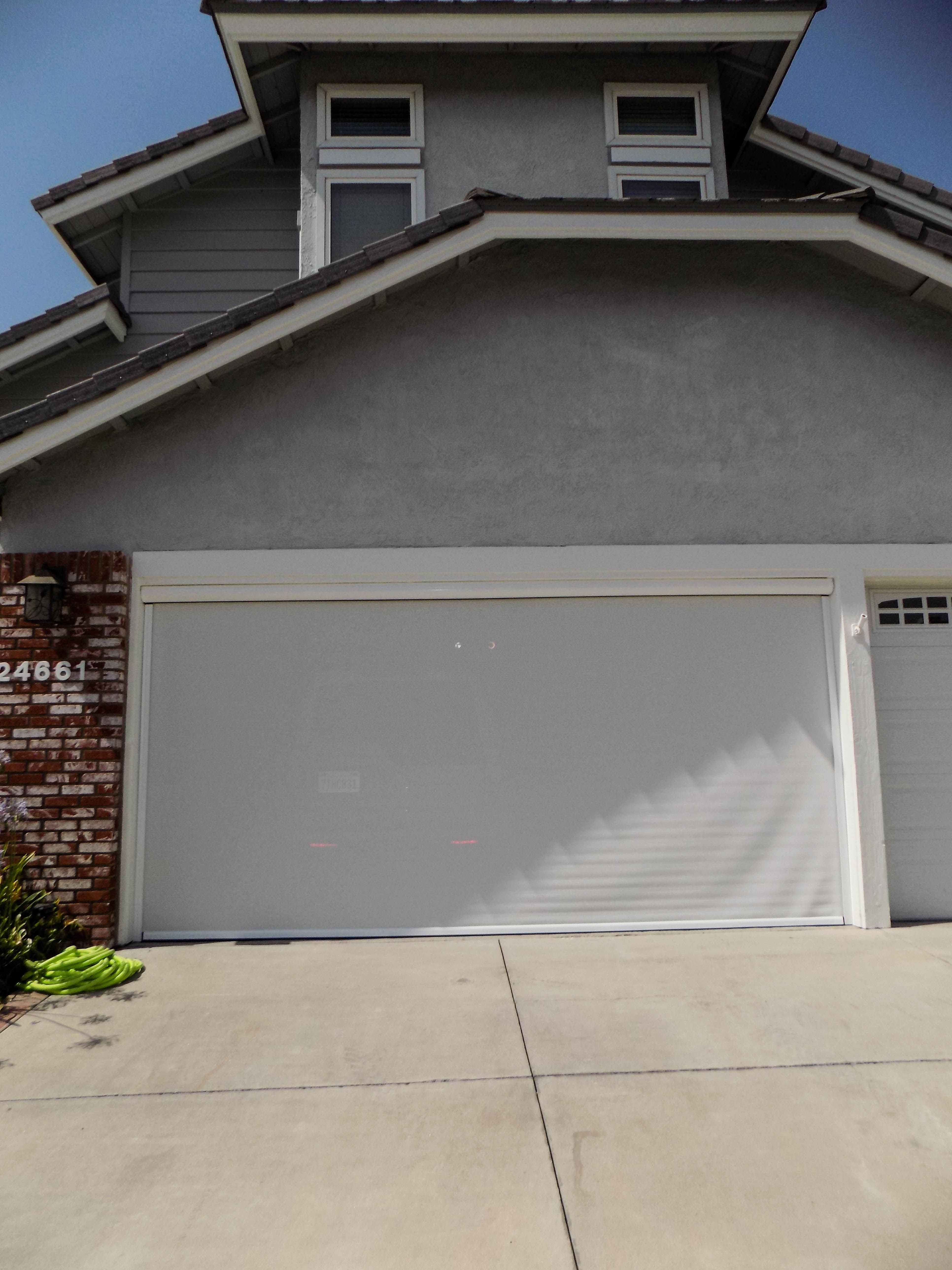 Motorized Power Screen with white solar screen and white housing
	 on a garage door